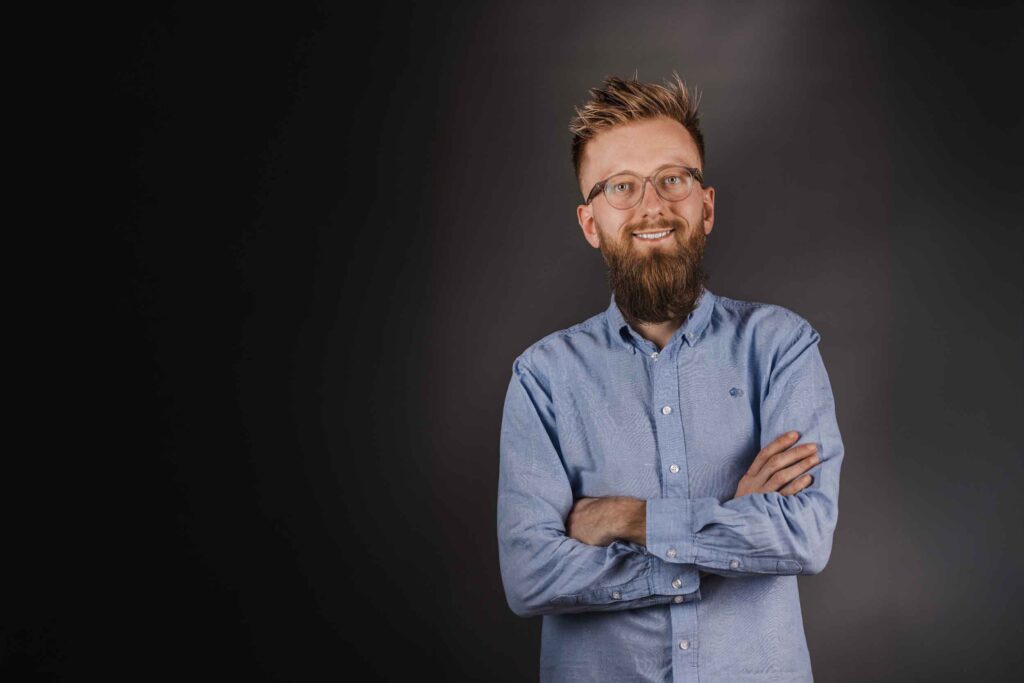 Philipp Donat, ein junger Mann mit Vollbart, lässt sich im Studio professionell fotografieren.